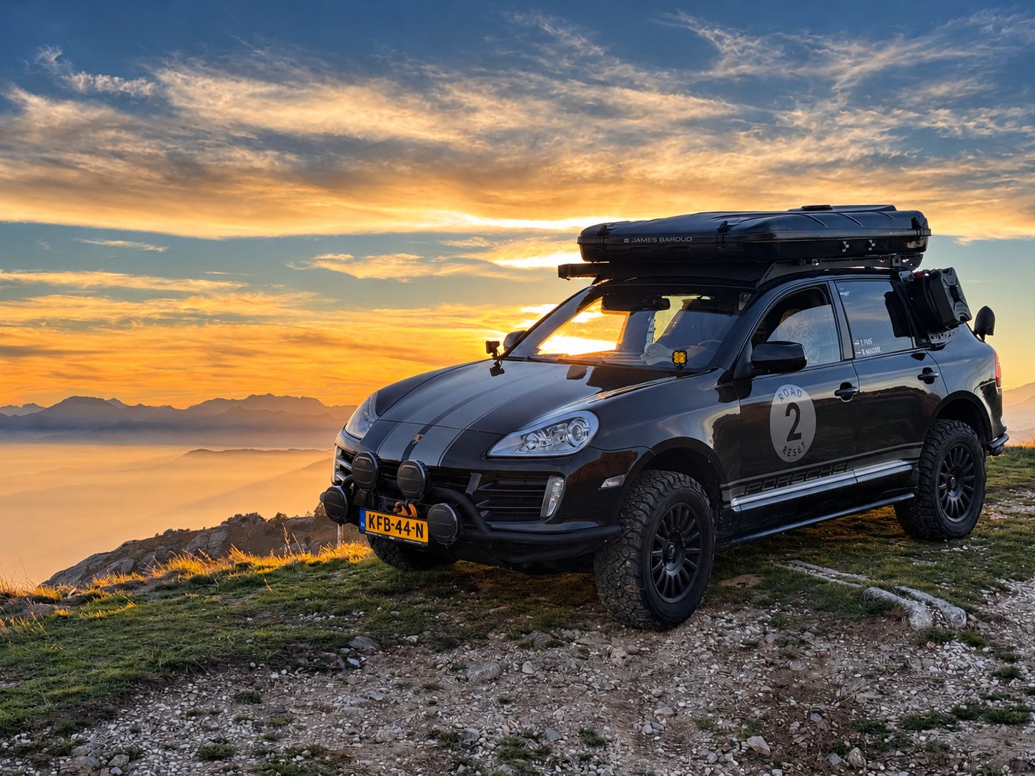 Our off-road Porsche Cayenne with roof tent on a mountain ridge at sunset