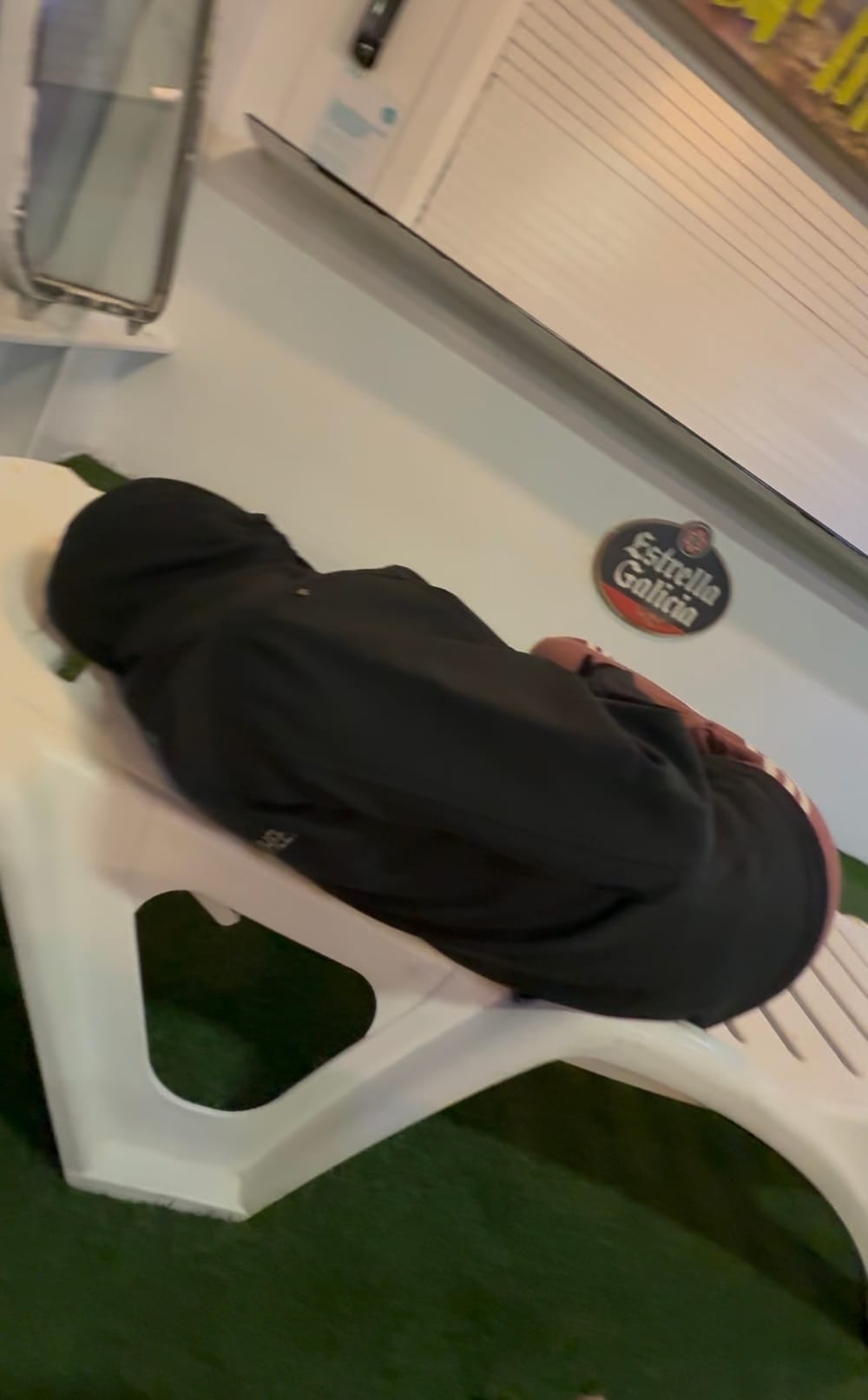 One of us curled up in a black hoodie on a white plastic sunlounger on the ferry's top deck